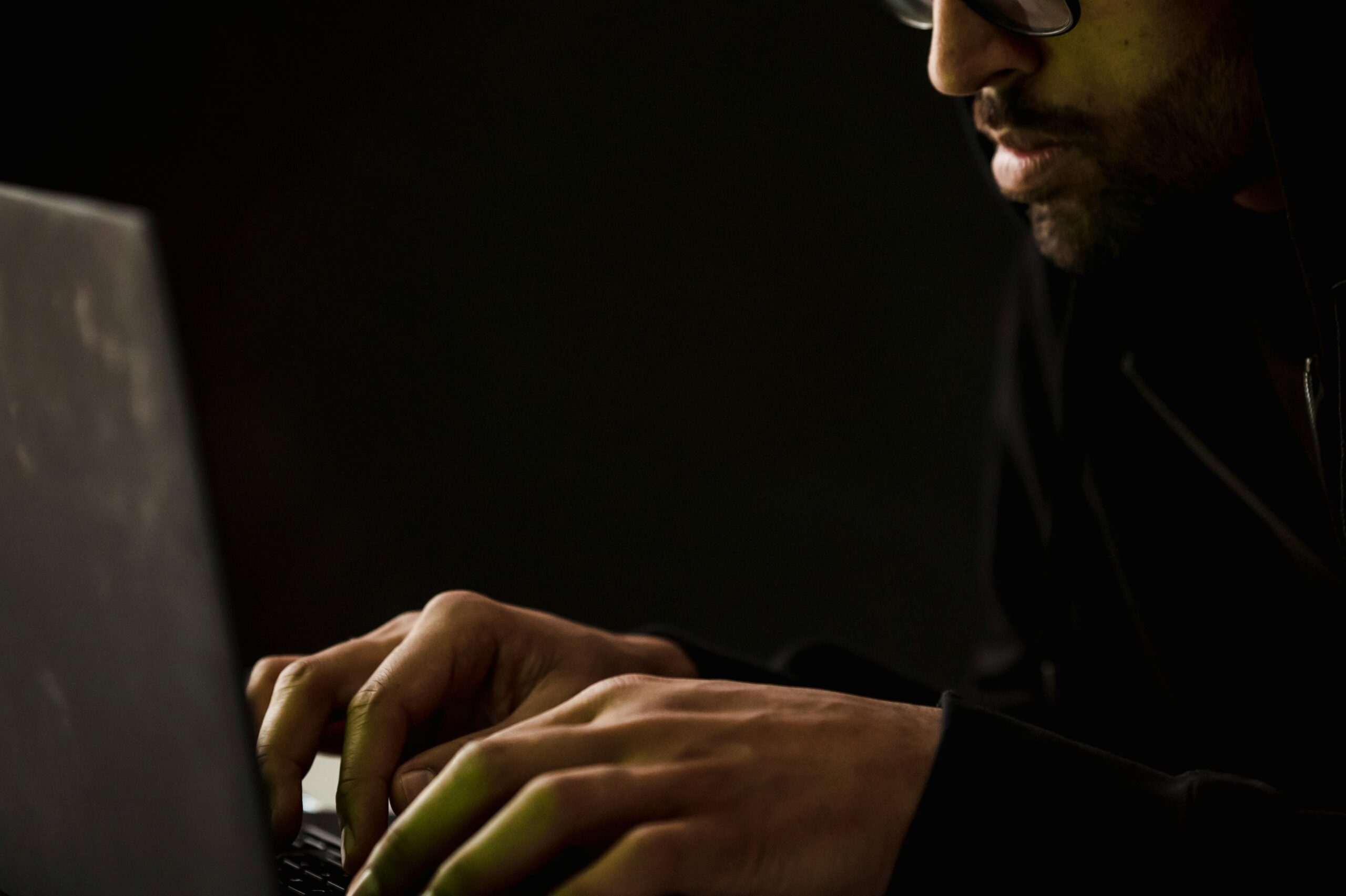 Close up of a man typing in a dark room